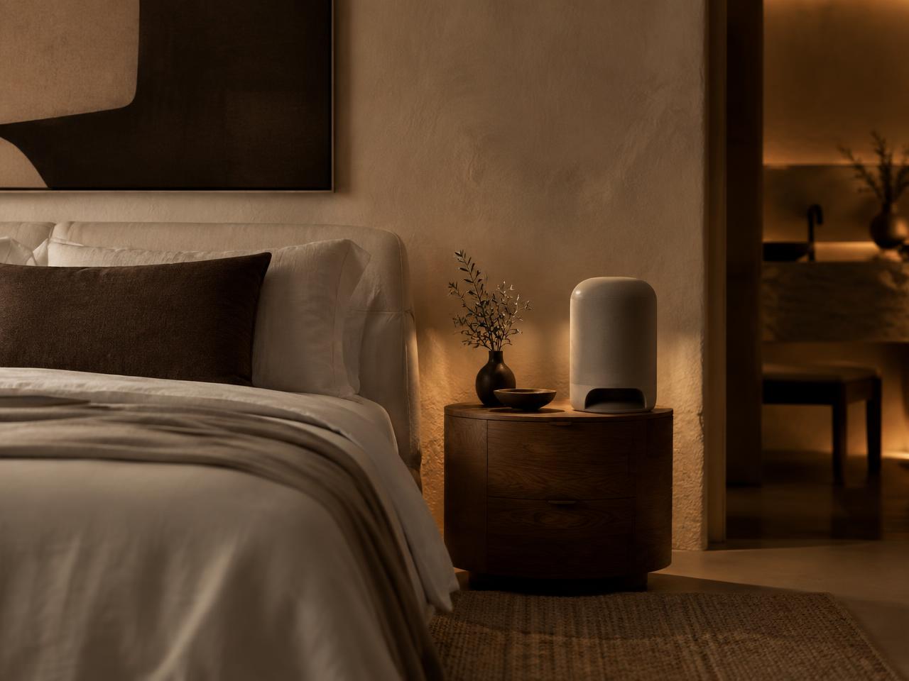 Linen bedroom at dusk with an air purifier on a nightstand